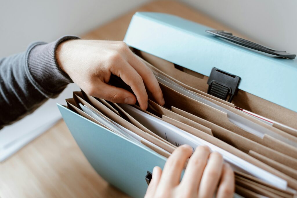 Filing cabinet filled with paperwork with a person's hands leafing through | Permits for Storage Building | Rooster's Amish Sheds, WV