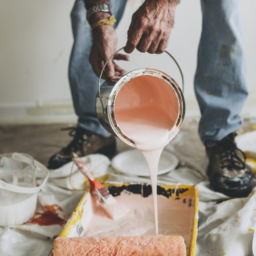 Man pouring white paint into a paint tin | Seasonal Shed Maintenance | Rooster's Amish Sheds, WV